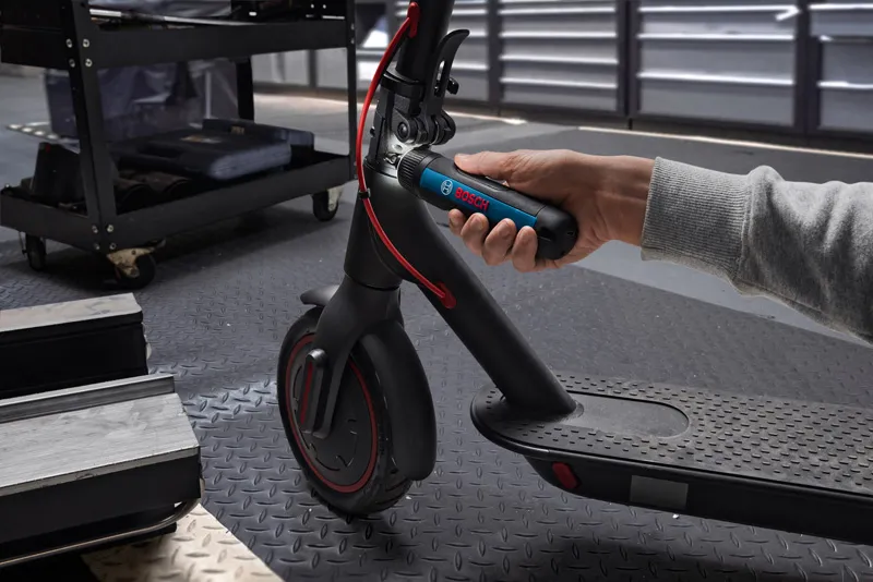 Một người sử dụng tua vít không dây để điều chỉnh tay lái của xe tay ga điện.