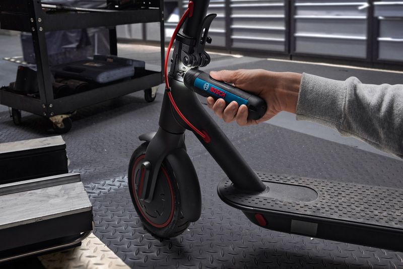 Một người sử dụng tua vít không dây để điều chỉnh tay lái của xe tay ga điện.