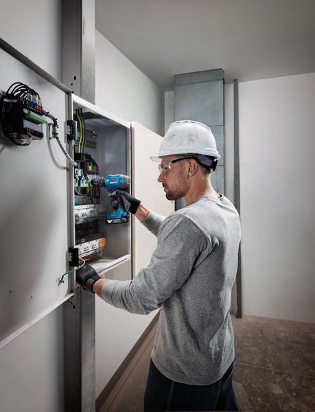 GSB 183-LI Người đeo thiết bị an toàn sử dụng máy khoan không dây trên bảng điện.