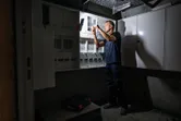 Một người đang làm việc trên bảng điện được chiếu sáng bằng đèn làm việc không dây.