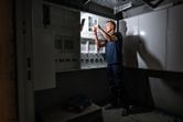 Một người đang làm việc trên bảng điện được chiếu sáng bằng đèn làm việc không dây.