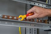 Một người đang siết chặt bu lông trên thanh đồng bằng cờ lê cách điện.