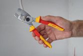 Một người đang cắt dây cáp điện bằng kìm cách điện.