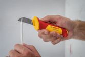 Một người sử dụng dao tiện ích cách điện để cắt dây điện.
