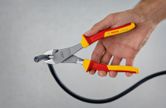 Một người sử dụng kìm cắt chéo cách điện để cắt một sợi cáp dày.