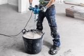 Một người mặc thiết bị an toàn đang trộn sơn bằng cơ chế khuấy điện.