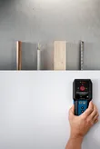 Một người sử dụng máy dò để quét tường để tìm kim loại, gỗ và dây điện.