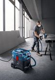 Một người mặc đồ bảo hộ đang cắt vật liệu bằng một chiếc cưa được kết nối với máy cắt đa năng.