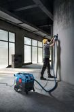 Một người mặc đồ bảo hộ đang mài bức tường bê tông bằng máy mài đa năng.