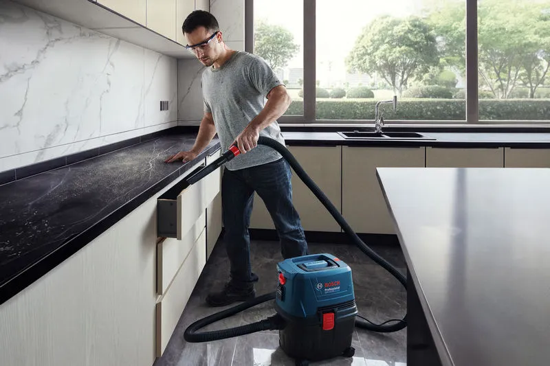 GAS 15 PS Một người mặc đồ bảo hộ sử dụng máy hút bụi khô ướt để vệ sinh tủ bếp.