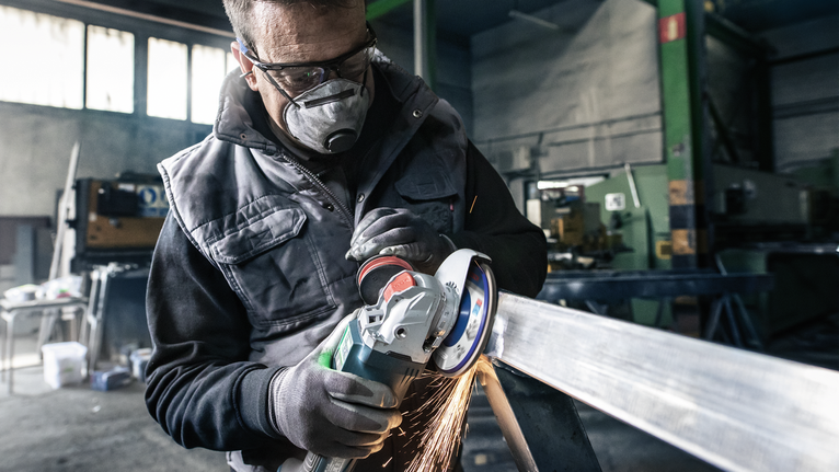 Người đeo thiết bị an toàn mài một thanh kim loại, tạo ra tia lửa.