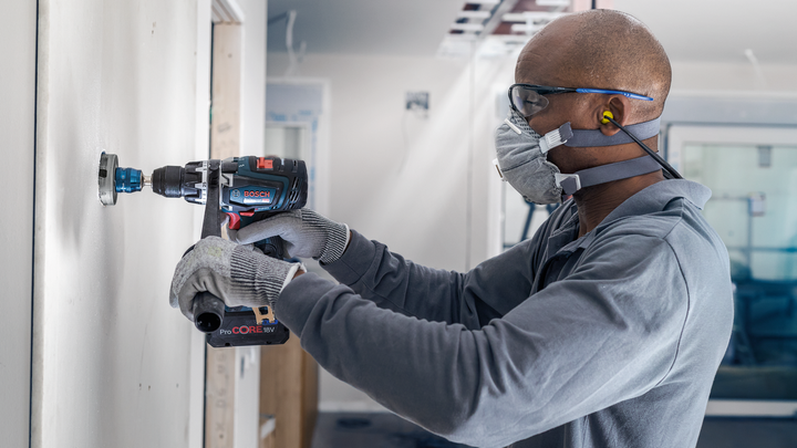 Người đeo thiết bị an toàn khoan một lỗ tròn vào bức tường bên trong.