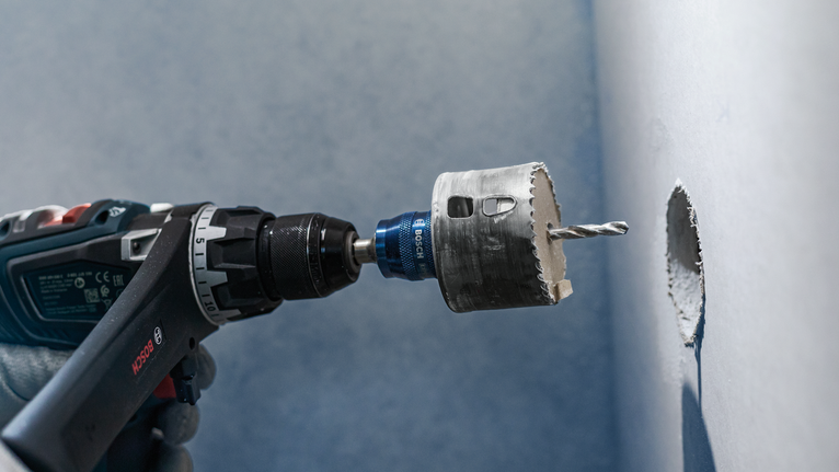 Người đeo thiết bị an toàn khoan một lỗ tròn vào tường.