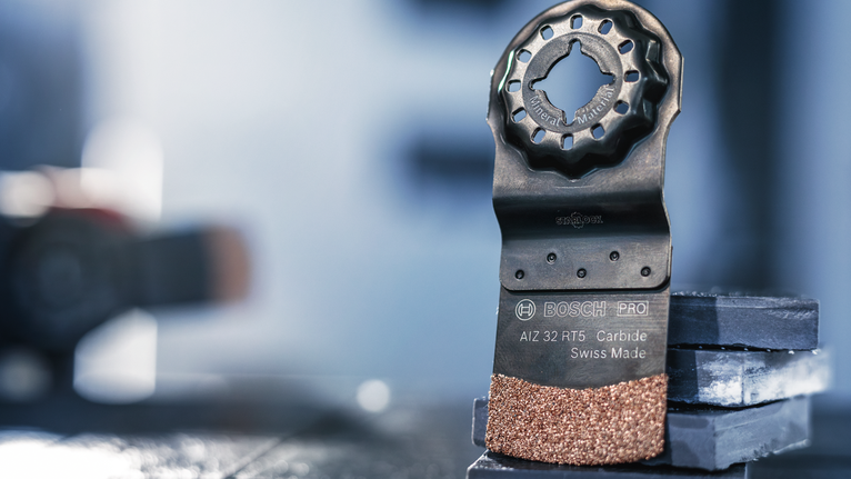 Lưỡi dao cacbua đa năng dao động đứng thẳng trên các viên gạch xếp chồng lên nhau.