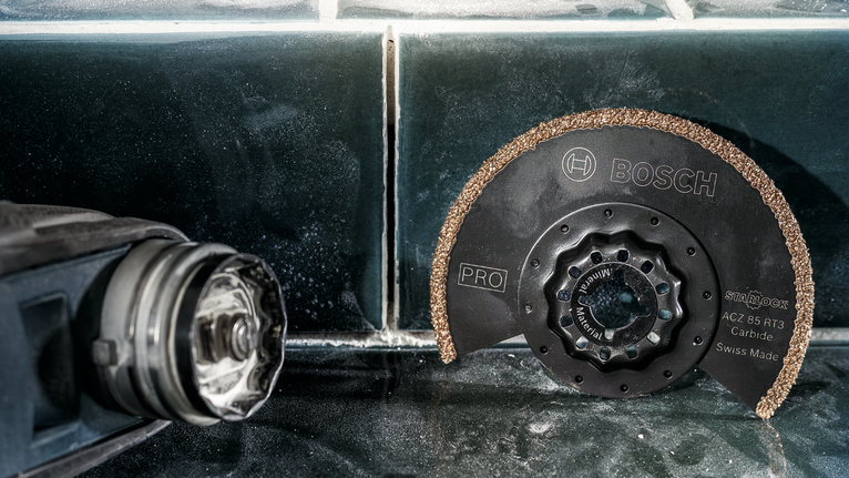 Lưỡi cưa cacbua tròn đặt trên bề mặt lát gạch cạnh một dụng cụ điện.