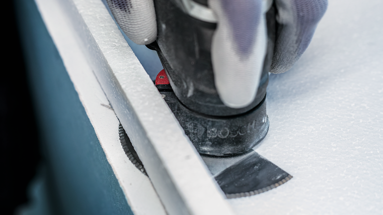 Người đeo thiết bị an toàn cắt tấm ván bằng lưỡi dao đa năng.