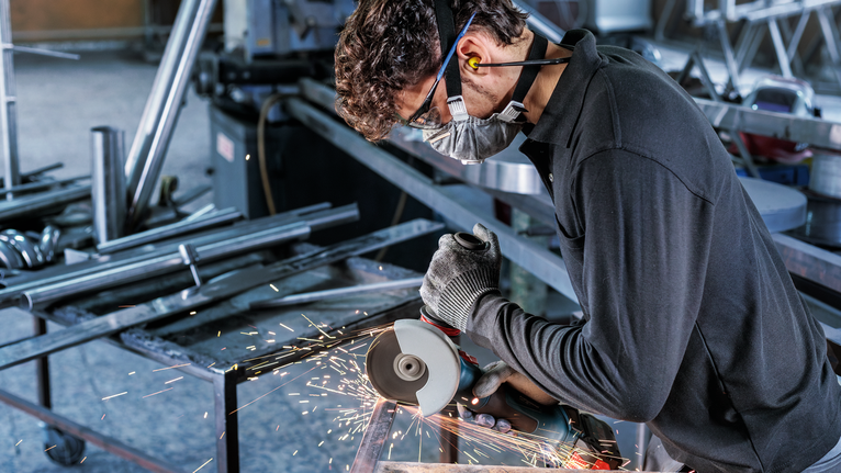 Người đeo thiết bị an toàn sử dụng máy mài góc để cắt kim loại, tạo ra tia lửa điện.