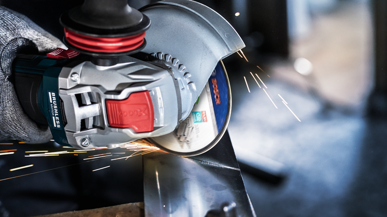 Một người mặc đồ bảo hộ sẽ mài kim loại, tạo ra tia lửa sáng.