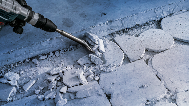 Công cụ phá dỡ đang phá vỡ các viên gạch bê tông tại một công trường xây dựng.