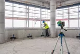 Người đeo thiết bị an toàn căn chỉnh vật liệu gần thiết bị cân bằng laser trên chân máy.