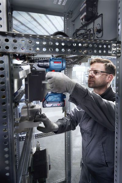 ISR 18V-30 P Một người mặc đồ bảo hộ đang sử dụng máy khoan không dây bên trong tủ điện.