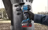 Một người mặc thiết bị an toàn đang sử dụng cờ lê lực không dây để siết chặt một cấu trúc kim loại lớn.
