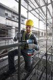 Một người mặc thiết bị an toàn đang sử dụng cờ lê lực không dây trên giàn giáo.