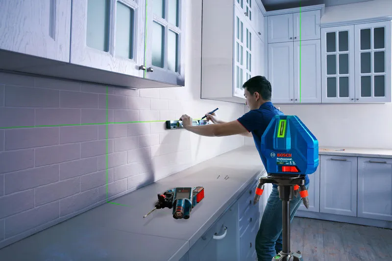 Một người đang sử dụng dụng cụ cân bằng bằng laser để căn chỉnh các tủ trong nhà bếp.