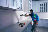 Người đang căn chỉnh tủ bếp bằng máy cân bằng laser trên giá ba chân.