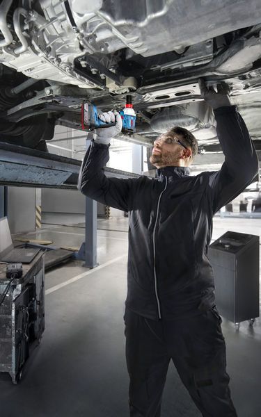 GDX 18V-285 Một người mặc thiết bị an toàn sử dụng máy khoan không dây dưới gầm xe đang nâng.