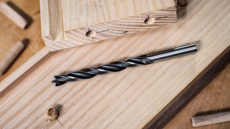 Bộ mũi khoan đầu đinh nhỏ PRO Wood, 7 chiếc Đặt mũi khoan trên ván gỗ có chốt gỗ gần đó.