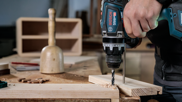 Bộ mũi khoan đầu đinh nhỏ PRO Wood, 7 chiếc Người đang sử dụng máy khoan điện để tạo lỗ trên tấm ván gỗ.