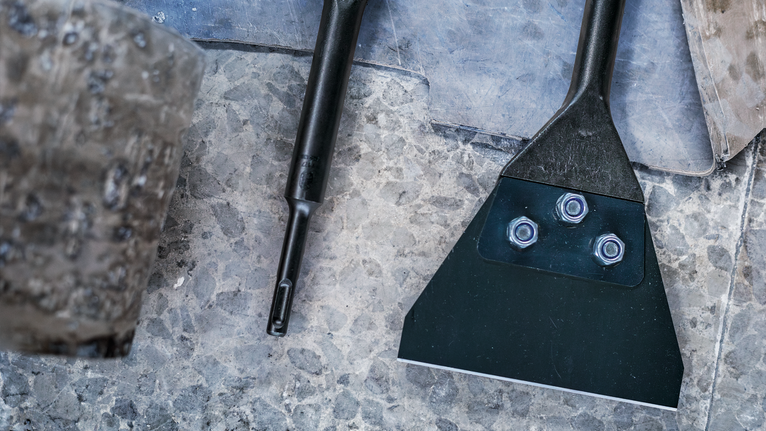 Đục kim loại rộng có bu lông đặt trên bề mặt đá có kết cấu.