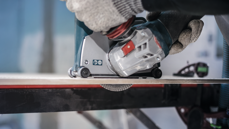 Người mặc đồ bảo hộ đang vận hành dụng cụ điện để cắt gạch.