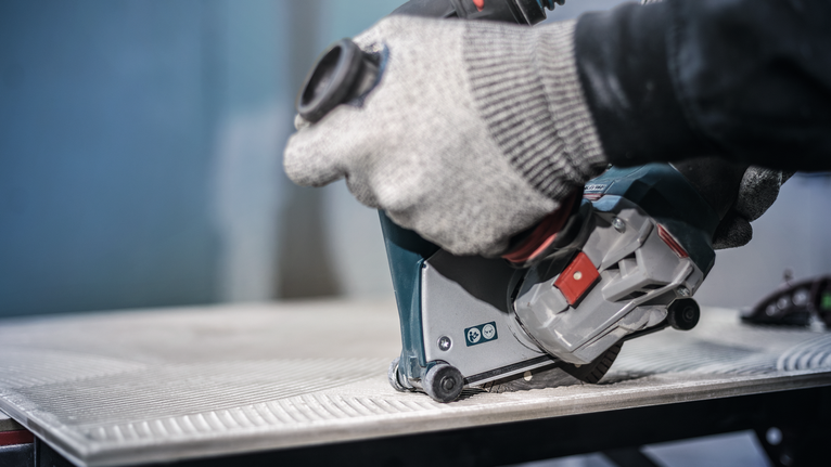 Người đeo thiết bị an toàn sử dụng dụng cụ điện để cắt gạch.