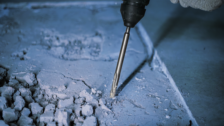 Một người mặc đồ bảo hộ sử dụng búa quay để phá bê tông.