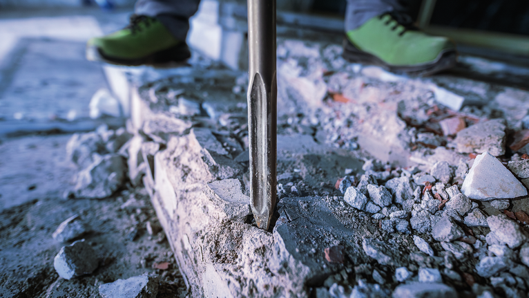 Người mặc đồ bảo hộ sử dụng dụng cụ phá dỡ để phá bê tông.