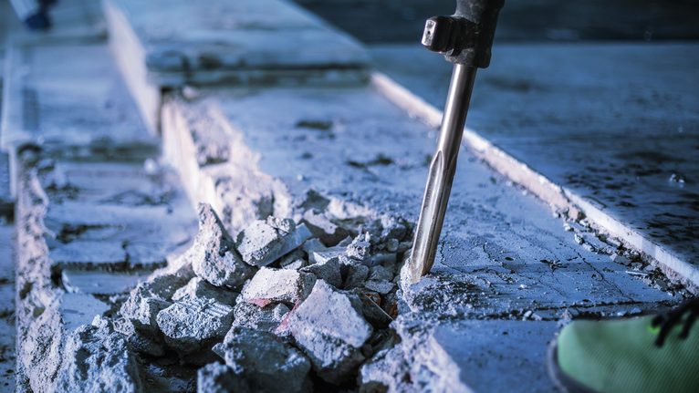 Búa phá dỡ đang phá vỡ bê tông tại một công trường xây dựng.