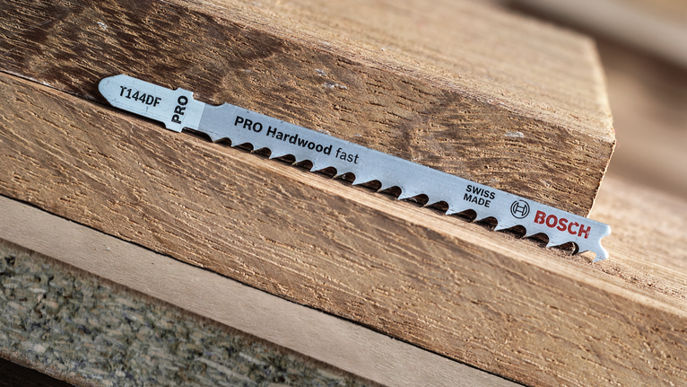 Lưỡi cưa lọng PRO Hardwood fast T144DF, 100 mm, 5 chiếc Lưỡi cưa lọng nằm trên những mảnh gỗ cứng xếp chồng lên nhau.