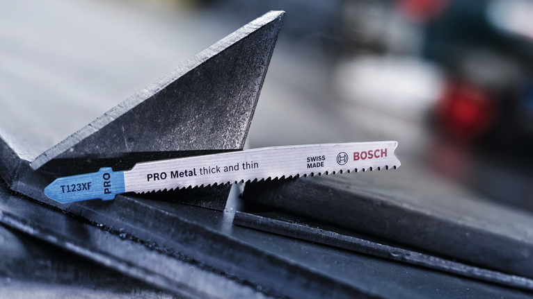 Lưỡi cưa lọng PRO Metal thick and thin T123XF, 100 mm, 5 chiếc Lưỡi cưa lọng nằm trên thanh kim loại trong môi trường công nghiệp.