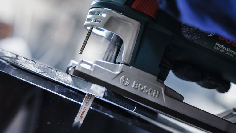 Lưỡi cưa lọng PRO Metal thick and thin T123XF, 100 mm, 5 chiếc Một người mặc đồ bảo hộ đang sử dụng máy cưa lọng để cắt một tấm kim loại màu đen.