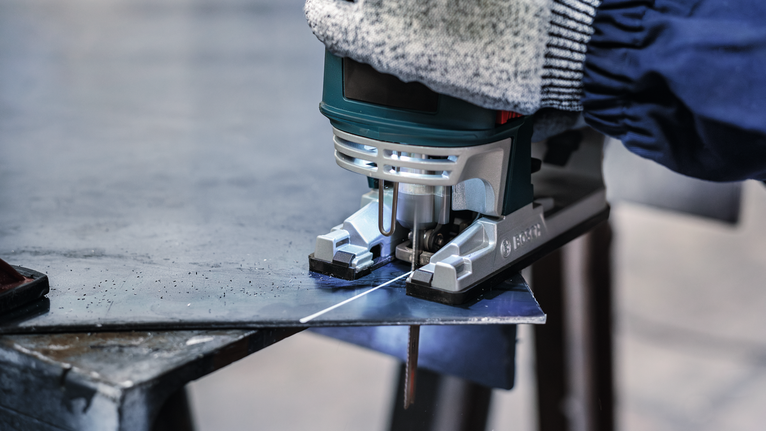 Lưỡi cưa lọng PRO Metal thick and thin T123XF, 100 mm, 5 chiếc Một người mặc đồ bảo hộ đang cắt một tấm kim loại bằng máy cưa lọng.