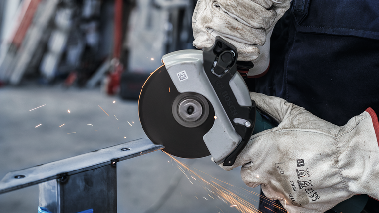 Đá cắt liên kết PRO Stainless Steel and Metal, 125 x 1,6 x 22,23 mm, X-Lock, thẳng, oSa Một người mặc đồ bảo hộ cắt kim loại bằng cưa tròn, tạo ra tia lửa.