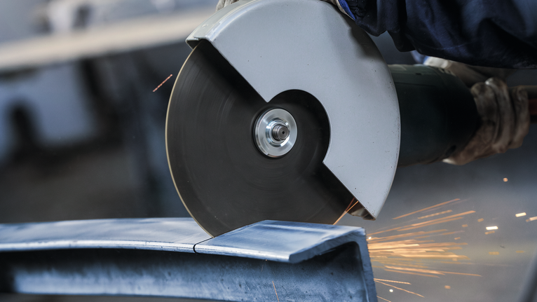 Đá cắt PRO Stainless Steel, 180 x 2 x 22,23 mm Một người mặc đồ bảo hộ đang cắt kim loại bằng máy mài góc lớn.