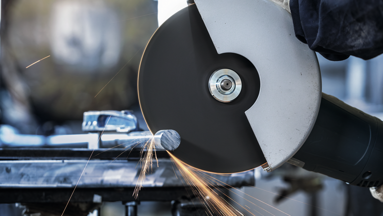 Đá cắt PRO Stainless Steel, 180 x 2 x 22,23 mm Người đeo thiết bị an toàn sử dụng máy mài góc lớn để cắt kim loại, có tia lửa bắn ra.