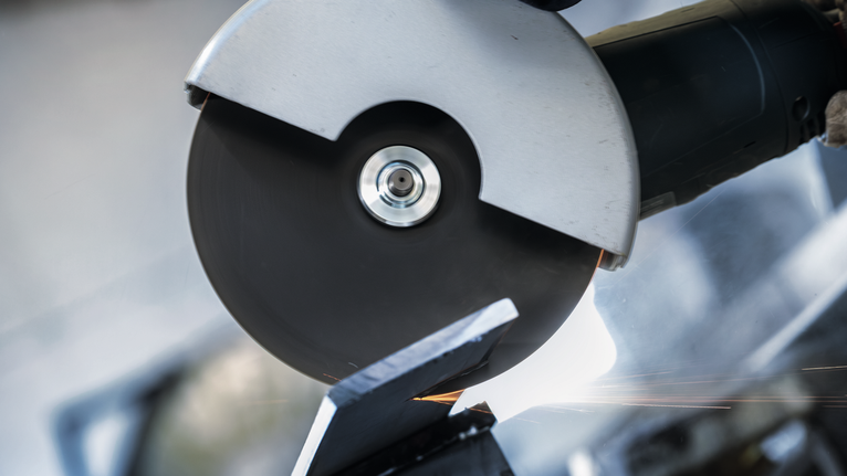 Đá cắt PRO Stainless Steel, 180 x 2 x 22,23 mm Một người mặc đồ bảo hộ sử dụng máy mài góc để cắt kim loại.