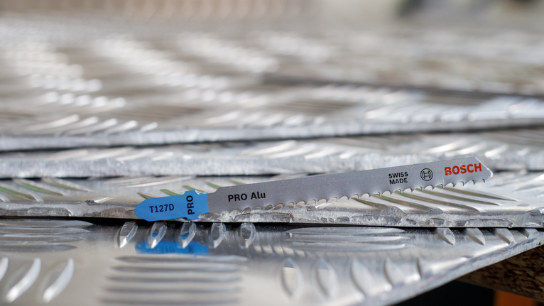 Lưỡi cưa lọng PRO Alu T127D, 100 mm, 5 chiếc Lưỡi cưa nằm trên các tấm kim loại có kết cấu xếp chồng lên nhau.