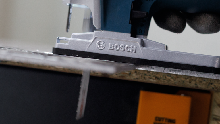 Lưỡi cưa lọng PRO Alu T127D, 100 mm, 5 chiếc Người đeo thiết bị an toàn đang điều khiển máy cưa lọng cắt xuyên qua một tấm gỗ.