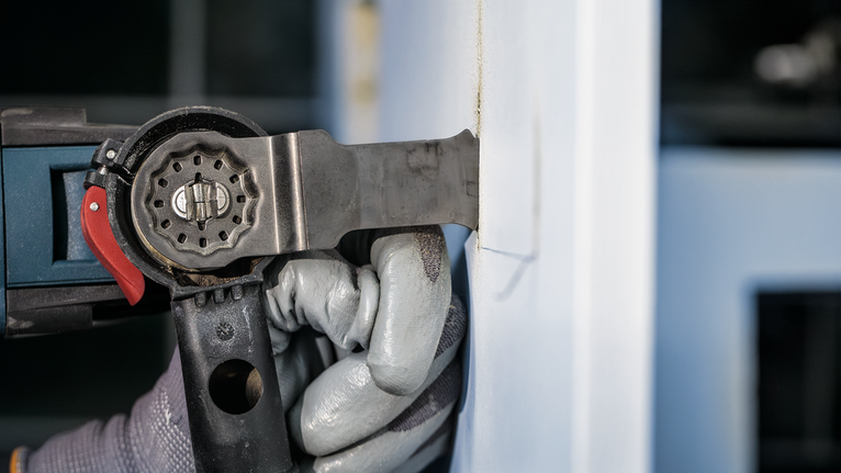 Người đeo thiết bị an toàn sử dụng dụng cụ điện để cắt tường.