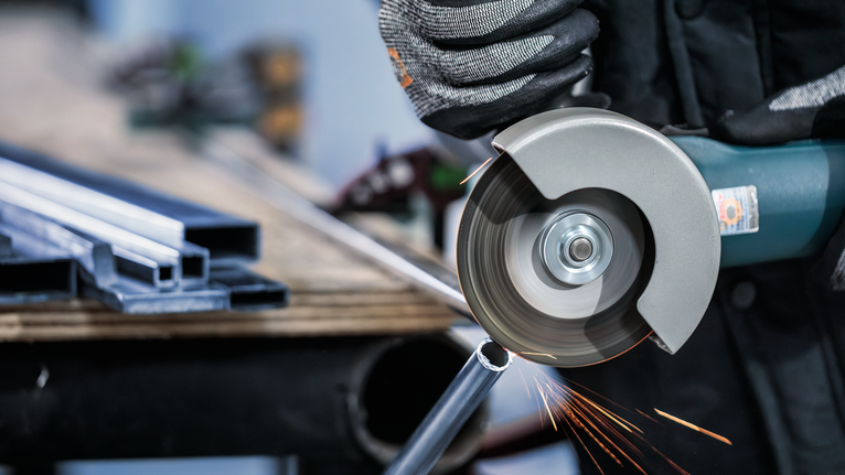 Đá cắt PRO Stainless Steel and Metal, 105 x 1 x 16 mm Một người mặc đồ bảo hộ đang cắt một ống kim loại bằng máy mài góc.